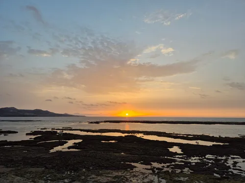 Sunset over the tide pools at Playa de Confital, Las Palmas, with Tenerife on the horizon
