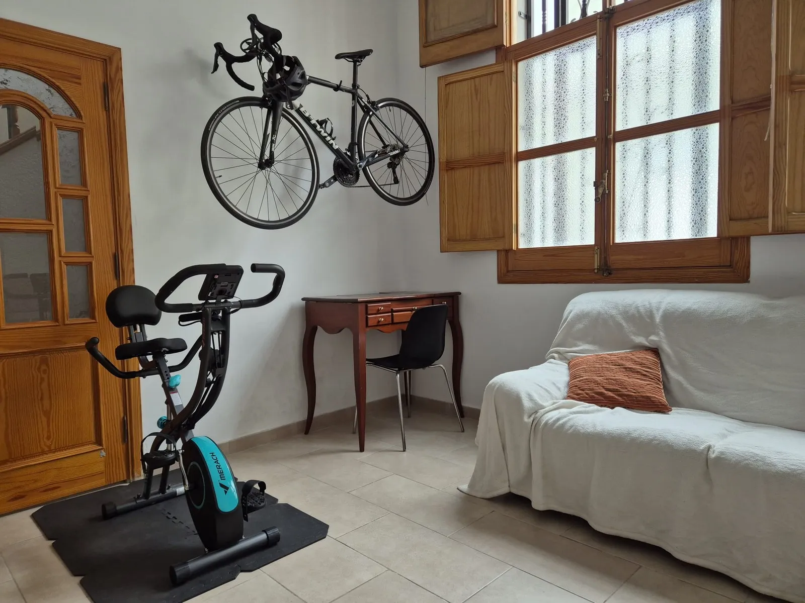 The living room at U32 with the racing bike mounted on the wall and the stationary bike on a mat in front of it