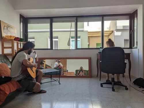 Someone playing acoustic guitar on the sofa while another person works at a desk, in the room that is now the silent coworking space