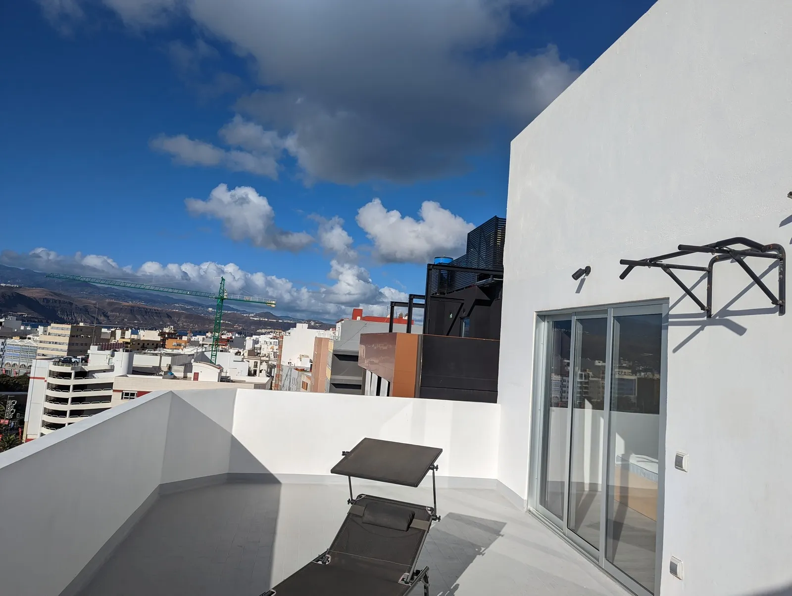 Southern terrace at J48 Penthouse - pull-up bar, blue sky, sunbed, city view