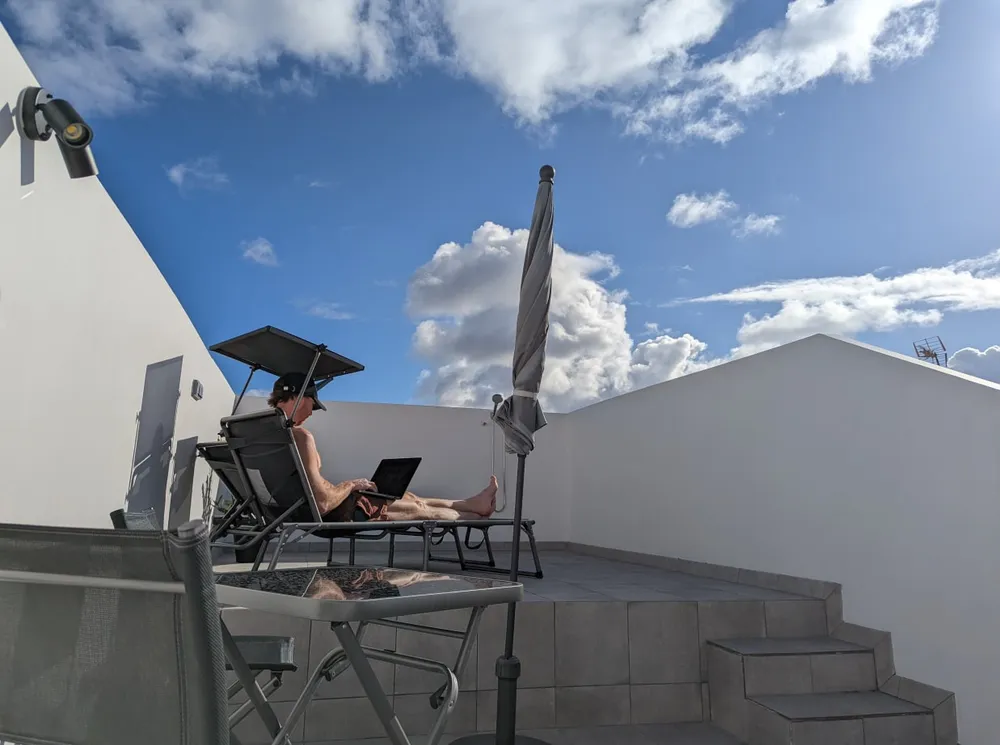 A resident working on a laptop from a sunbed on the sun terrace at U32 in Las Palmas